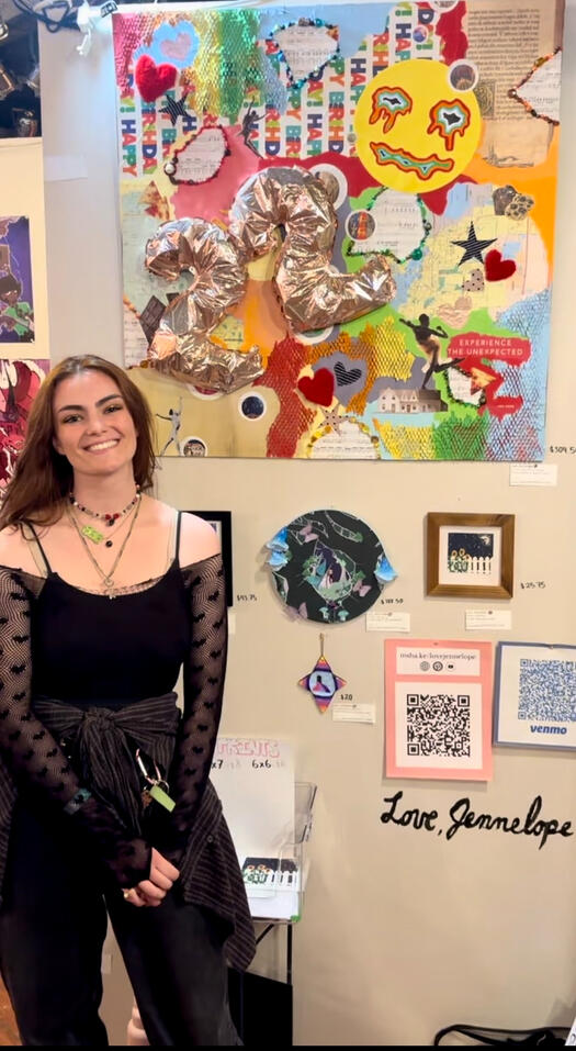 The artist stands in front of five of her art pieces at an exhibition.